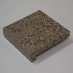 A square stone sample block of brown, grey, and tan speckled engineered quartz featuring a straight eased edge profile.