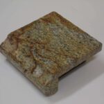 A small square sample block of tan and gold granite featuring reddish-brown veining and a finished ogee edge profile.