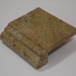 A small square sample block of tan and gold granite with an ogee over full bullnose edge profile.