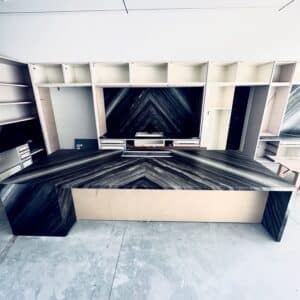 Modern kitchen under construction featuring custom book-matched dark marble island and backsplash surrounding white cabinetry frames.