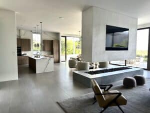 Modern open-concept living area and kitchen featuring a floating concrete fireplace wall with TV.