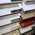 Angled view of Q Premium Natural Quartz sample slabs with name labels displayed on a metal rack.