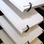 Close-up of white and off-white quartz sample slabs on a display rack with black wire holders.