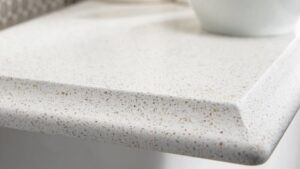 Close-up of a white and beige speckled quartz countertop corner with a beveled edge profile.