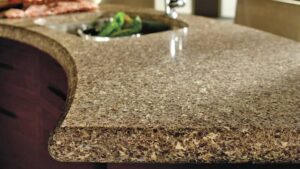 Close-up of a curved brown speckled quartz countertop featuring a smooth bullnose edge and a prep sink in the background.